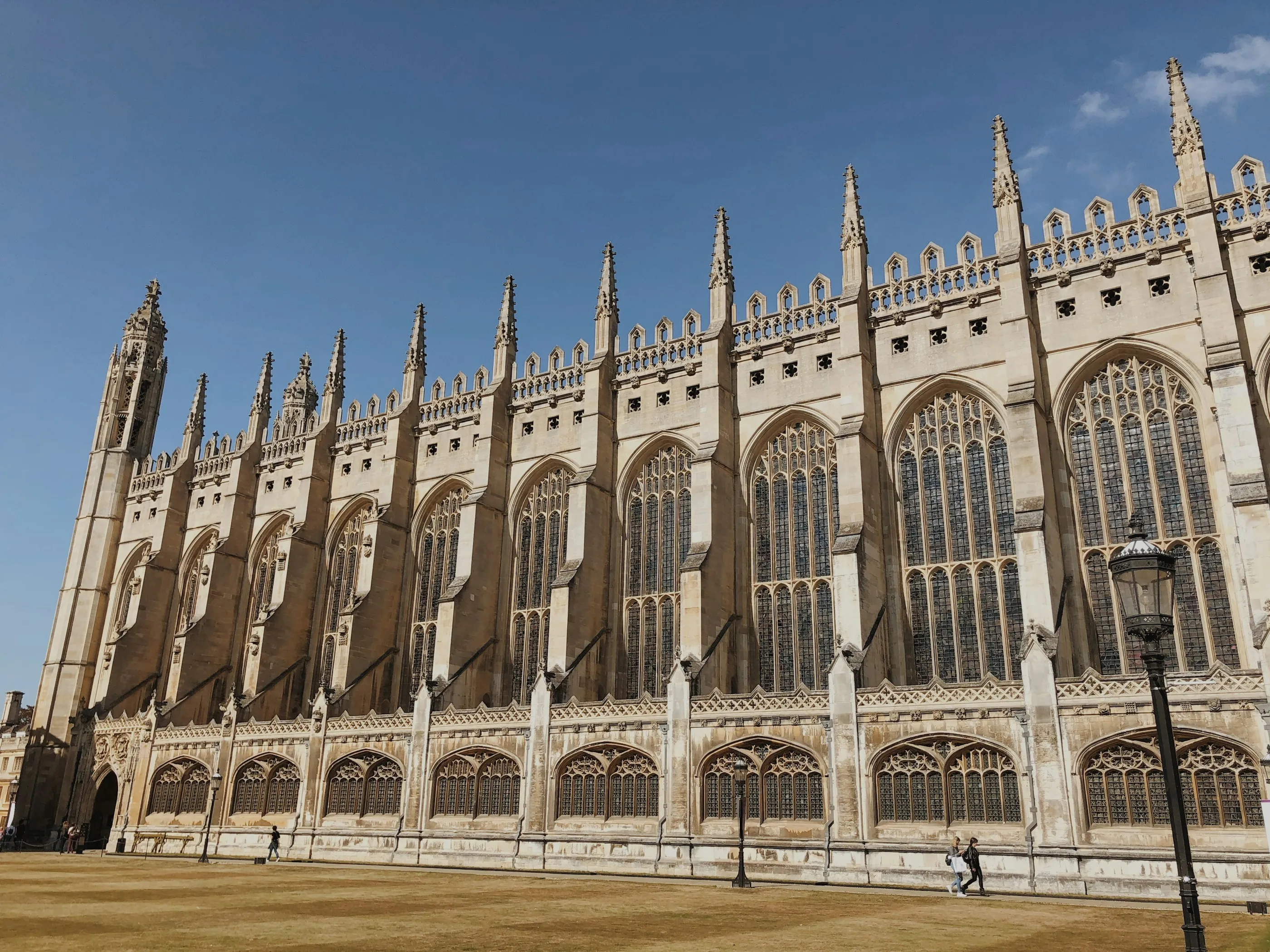 King's College Chapel viewed from its front court in daylight, pale Cambridge stone and gothic tracery rising against the sky.