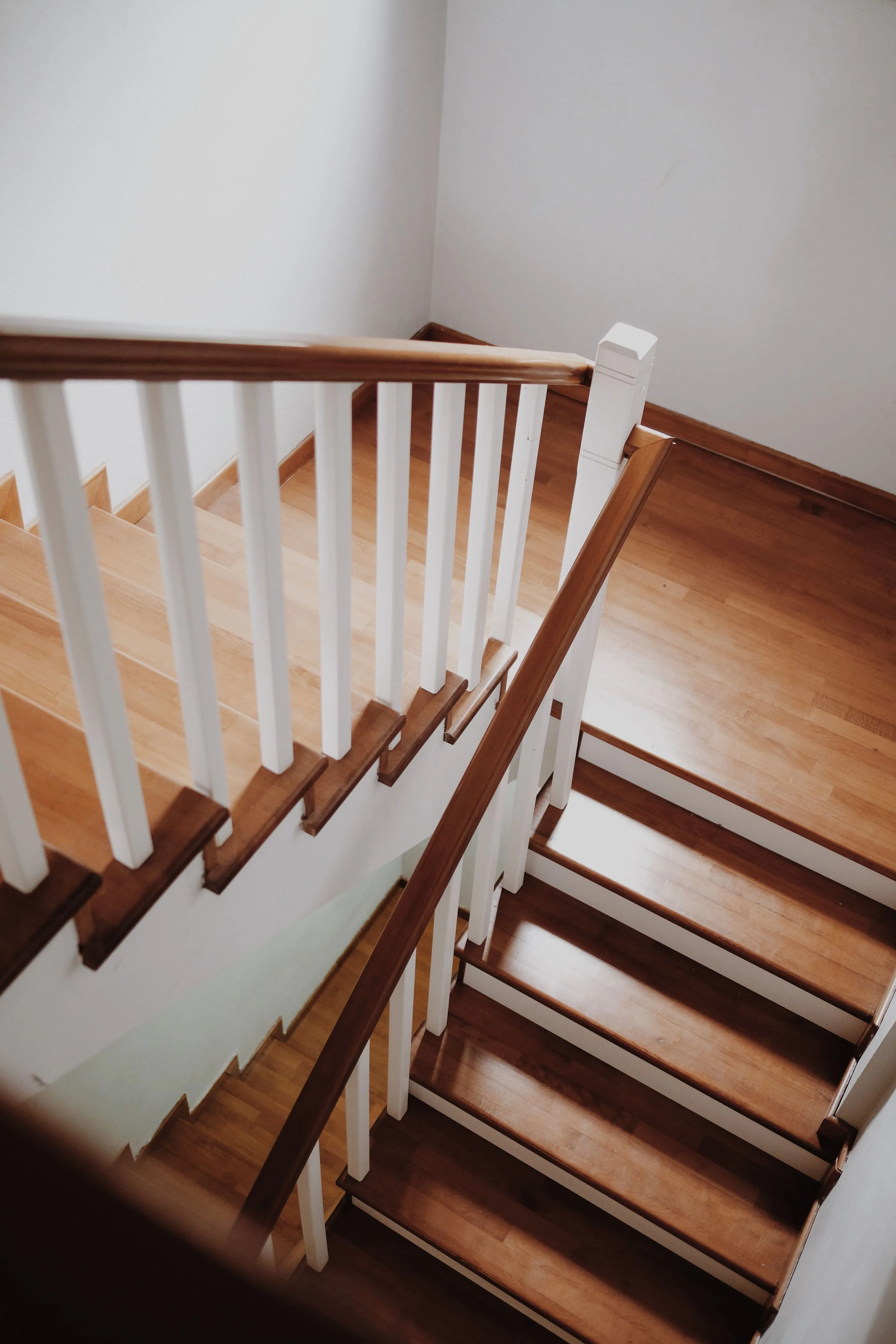 Warm daylight falling across a polished oak staircase in a well-kept home.